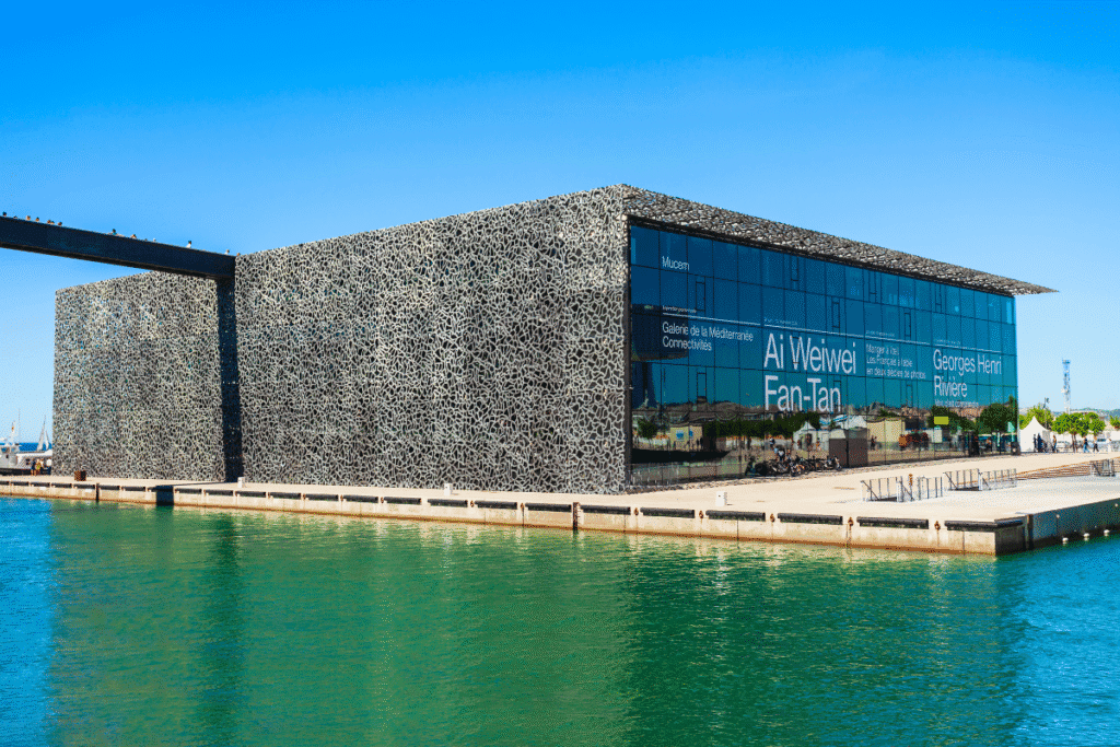 Modern waterfront view of the MuCEM museum in Marseille, with its intricate lattice-style exterior and glass walls reflecting the harbor, a contemporary cultural stop to include on any Marseille itinerary.