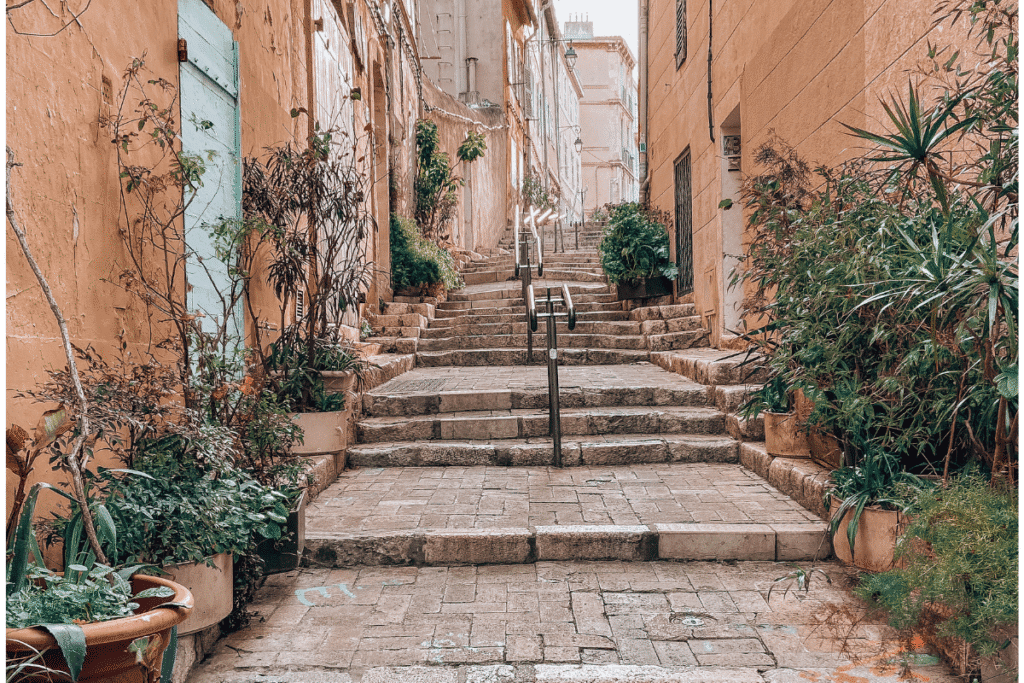 Stone stairway in Le Panier, Marseille’s oldest neighborhood, framed by terracotta buildings and vibrant potted plants. This picturesque alleyway captures the historic charm and artistic flair that makes Le Panier a must-visit on any Marseille itinerary.