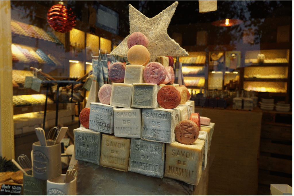 Display of colorful Savon de Marseille soaps stacked in a festive pyramid with a star on top, showcased in a local Marseille shop, a traditional souvenir to discover on any Marseille itinerary.