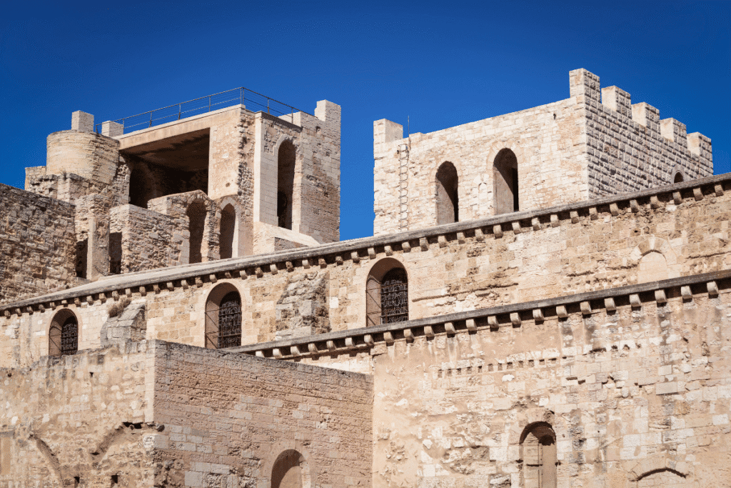 Stone façade and fortified towers of the Abbaye Saint-Victor in Marseille, showcasing its medieval architecture under a clear blue sky, an important historic site to visit on any Marseille itinerary.