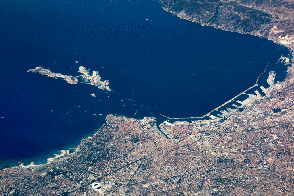 Aerial view of Marseille shows the city’s dense urban landscape along the Mediterranean coast, with the Vieux Port, nearby islands, and deep blue sea clearly visible. This striking perspective highlights the mix of coastline, harbors, and landmarks that make travel to Marseille a memorable experience.