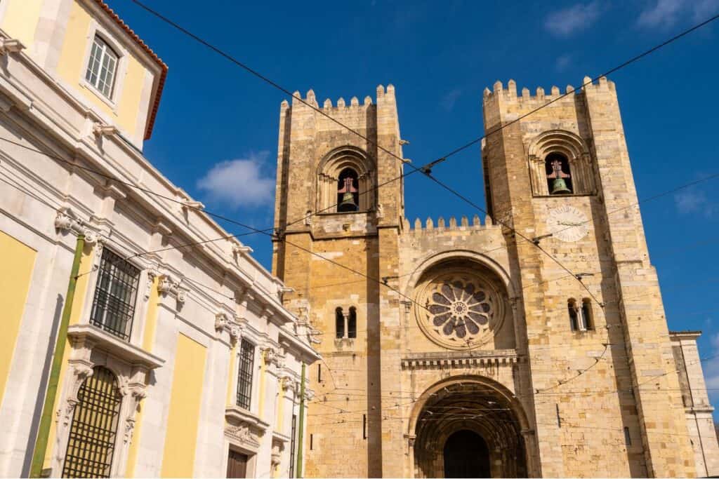 Lisbon Cathedral facade shows two large bell towers and a circular rose window above the main entrance under a clear blue sky. The city’s oldest church is a must see during a 3 day itinerary Lisbon.