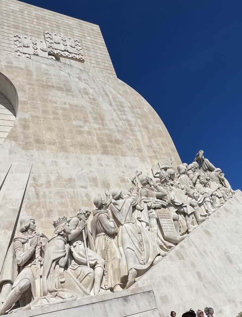 Monument of the Discoveries in Belém, Lisbon, featuring sculpted figures of Portuguese explorers facing the Tagus River under a clear blue sky, a striking historical stop on a Lisbon itinerary.