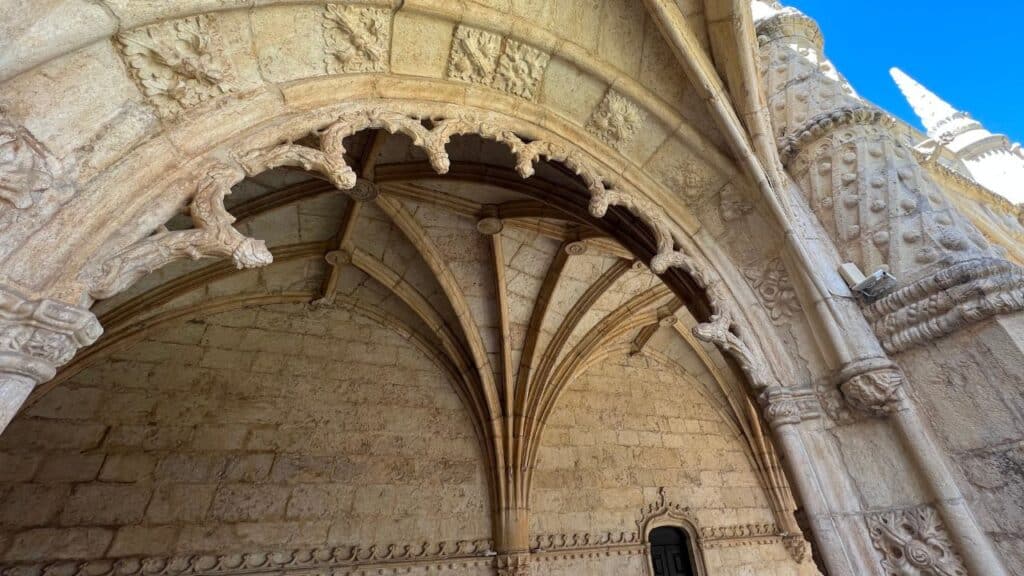 Detailed stone arch and vaulted ceiling inside Jerónimos Monastery decorated with carved symbols shells and floral patterns. The craftsmanship highlights the distinctive Manueline architecture Lisbon style.