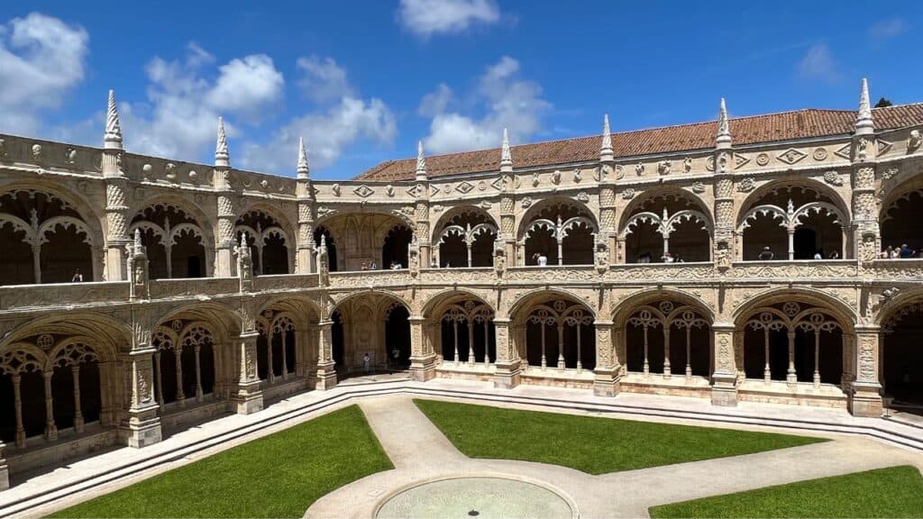 Peaceful cloister courtyard at Jerónimos Monastery surrounded by two levels of arches and detailed stone columns. The symmetrical design and carvings showcase classic Manueline architecture Lisbon.