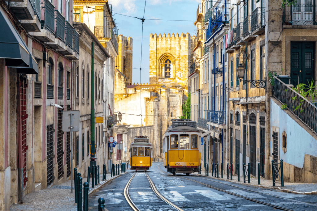 A traditional yellow tram climbing the steep, narrow streets of Lisbon's historic Alfama district.