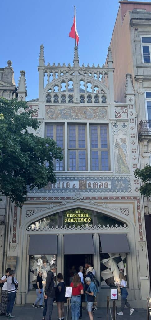 The facade of Livraria Lello with decorative arches and a red flag above as people line up outside the entrance. Visiting this famous bookstore is one of the most popular things to do in Porto.