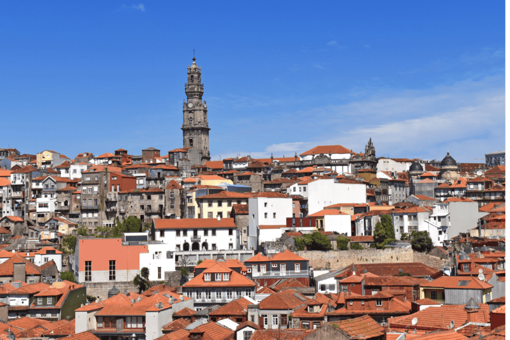 A dense hillside of red tiled rooftops and historic buildings stretches across Porto with a tall church tower rising above. The view highlights the layered architecture you explore when deciding how many days in Porto.