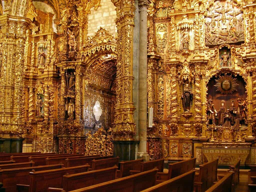 Gilded Baroque woodwork covers the walls and arches inside São Francisco Church in Porto. Wooden pews face elaborate carved altars that show the city’s rich religious art and architecture.
