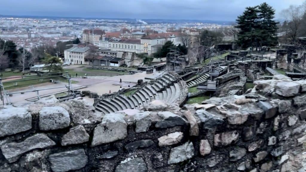 The ancient Roman Theatre of Fourvière ruins in Lyon, France with stone seating terraces and modern city views.