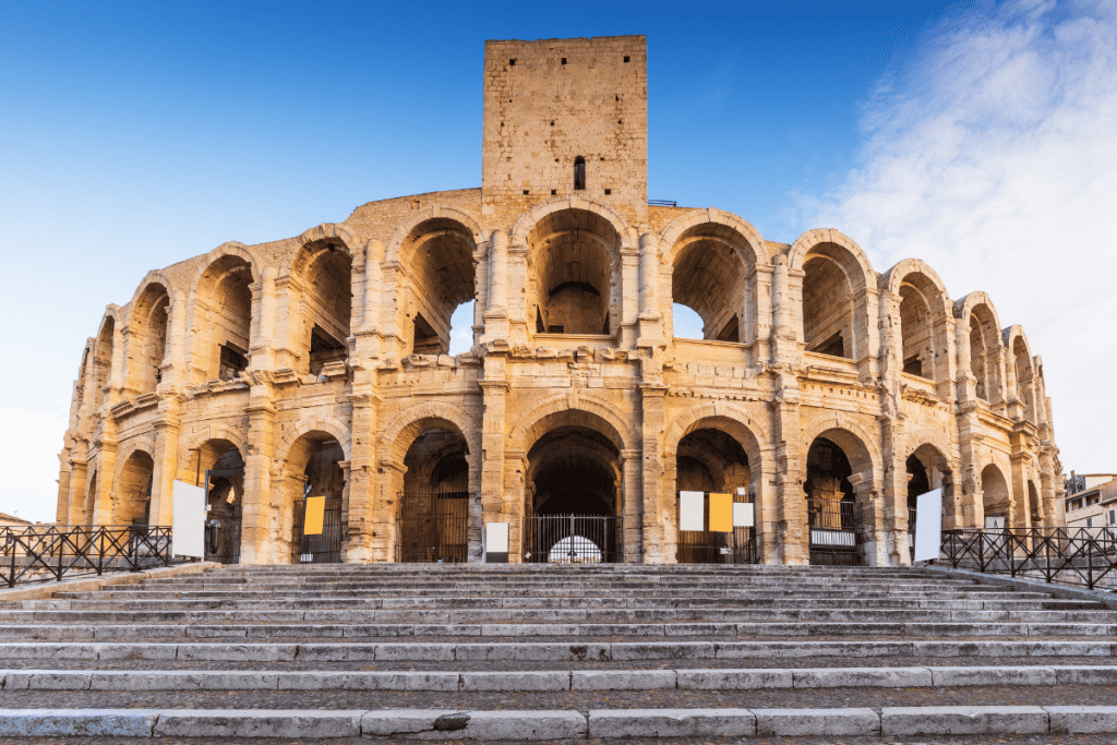 Well-preserved Roman amphitheater in Arles France under a bright blue sky.