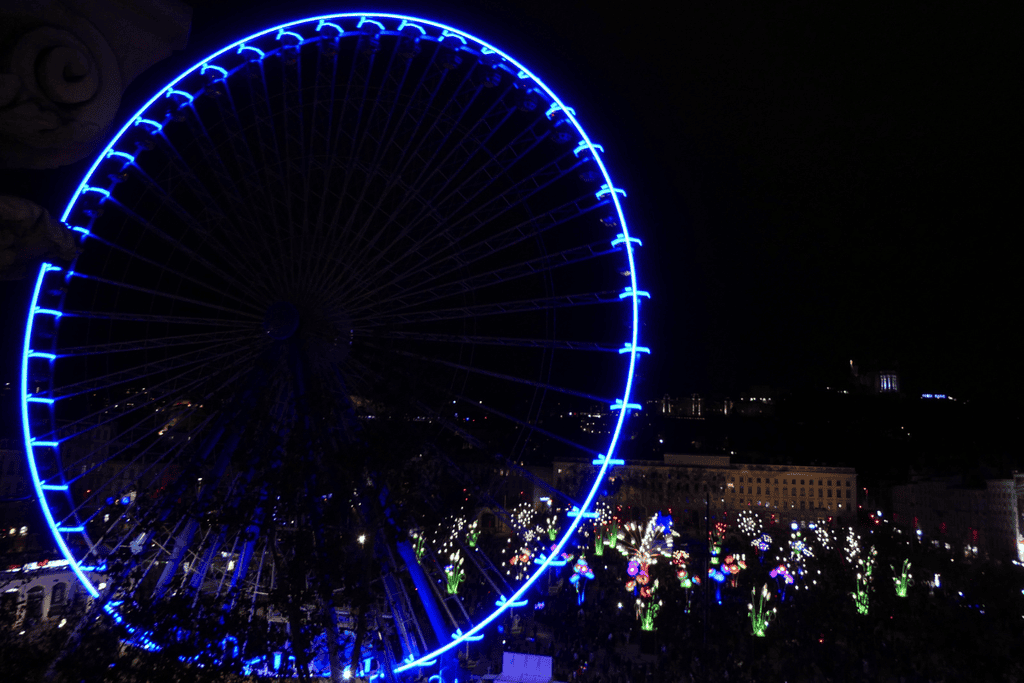 Illuminated Ferris Wheel and flowers, in the Place Bellacour in Lyon during the December Fête des Lumières light festival.