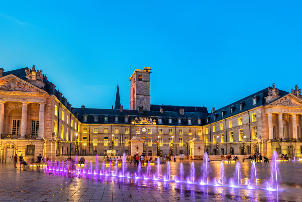 Palace of the Dukes of Burgundy in the UNESCO World Heritage historic center of Dijon France at dusk with illuminated water feature.